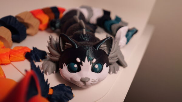 Two cat-like figures: one orange and cream, one black and white with teal eyes; other figures are behind them.