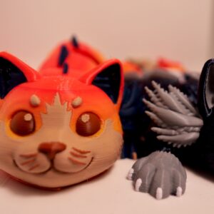 Axolotl Cat, orange and cream figure Several cat-like figures in orange, cream, black, and gray, with frilled details; a black-and-white figure is partly cropped.