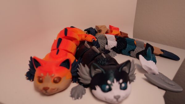 Group of colorful cat-like figures, with orange and black-and-white figures in front and segmented bodies behind.